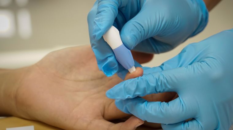 Health care worker taking blood sample from a hand