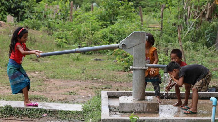 Children working a water pump