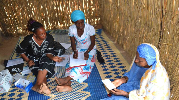 Health care worker discussing with patients in a hut