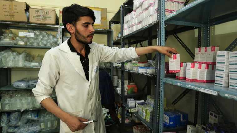 Health worker sorting prescriptions on shelves