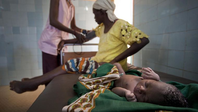 Mother and child on a healthcare bed. The mother is being checked by a health care worker