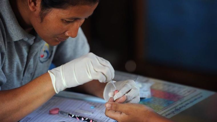 Health worker performing a blood test on a child