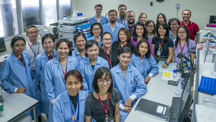 Group picture of the Clinical Pharmacology. They are in a lab and all wearing blue lab coats